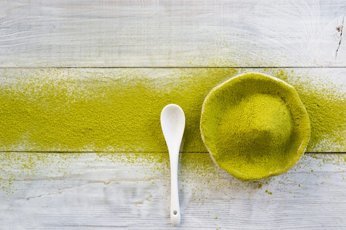 matcha green tea powder in ceramic plate on white wooden table 
