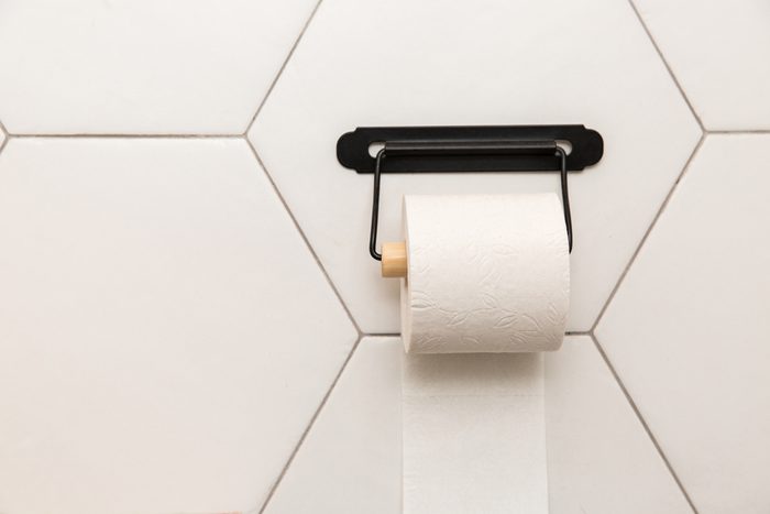 A white roll of toilet paper hanging in bathroom