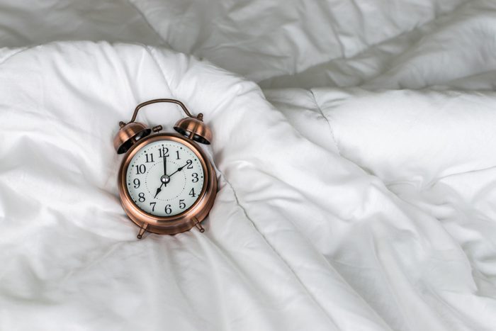 vintage alarm clock on the white bed with copy space.
